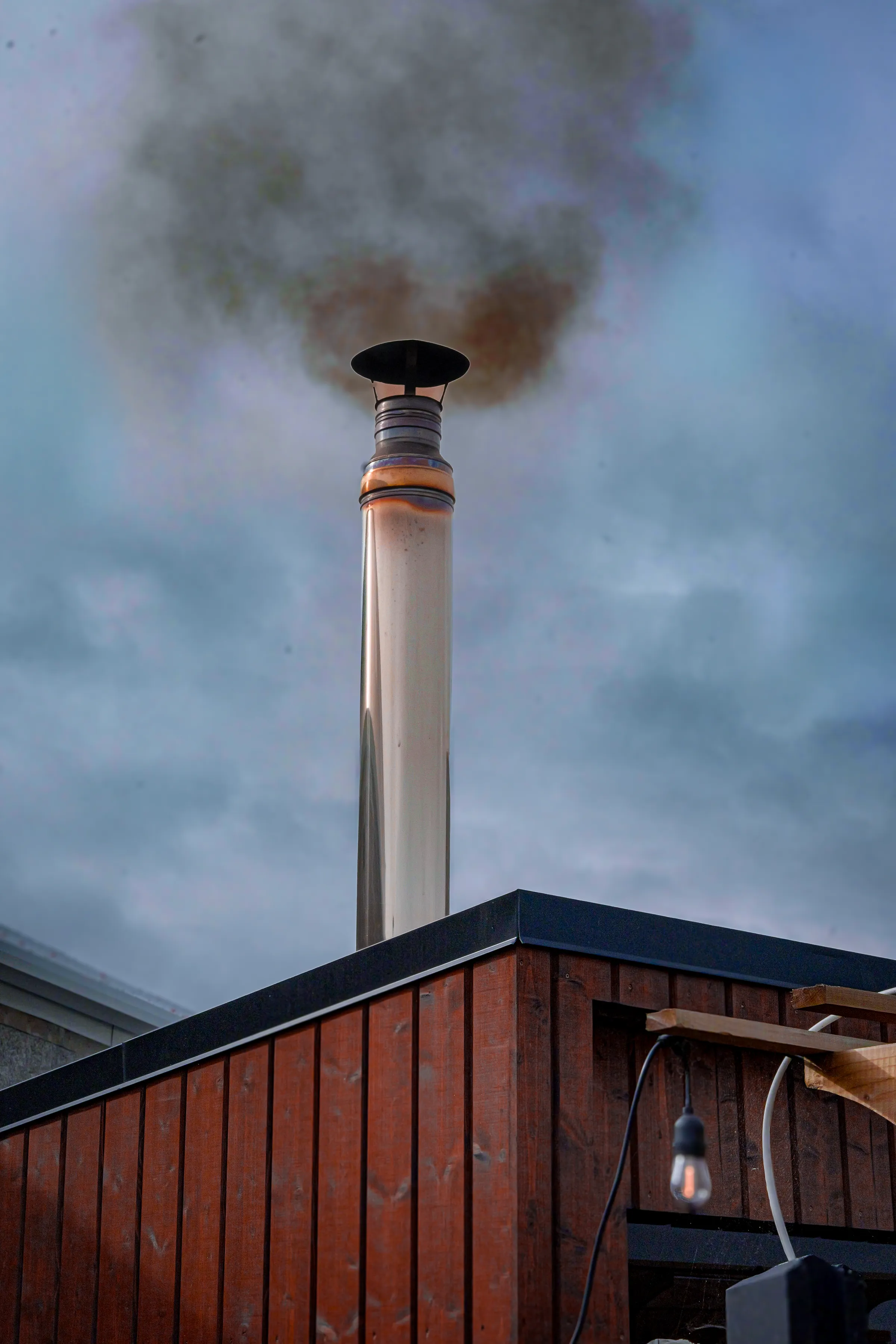 Smoke rising from the wood-fired sauna's chimney at dusk