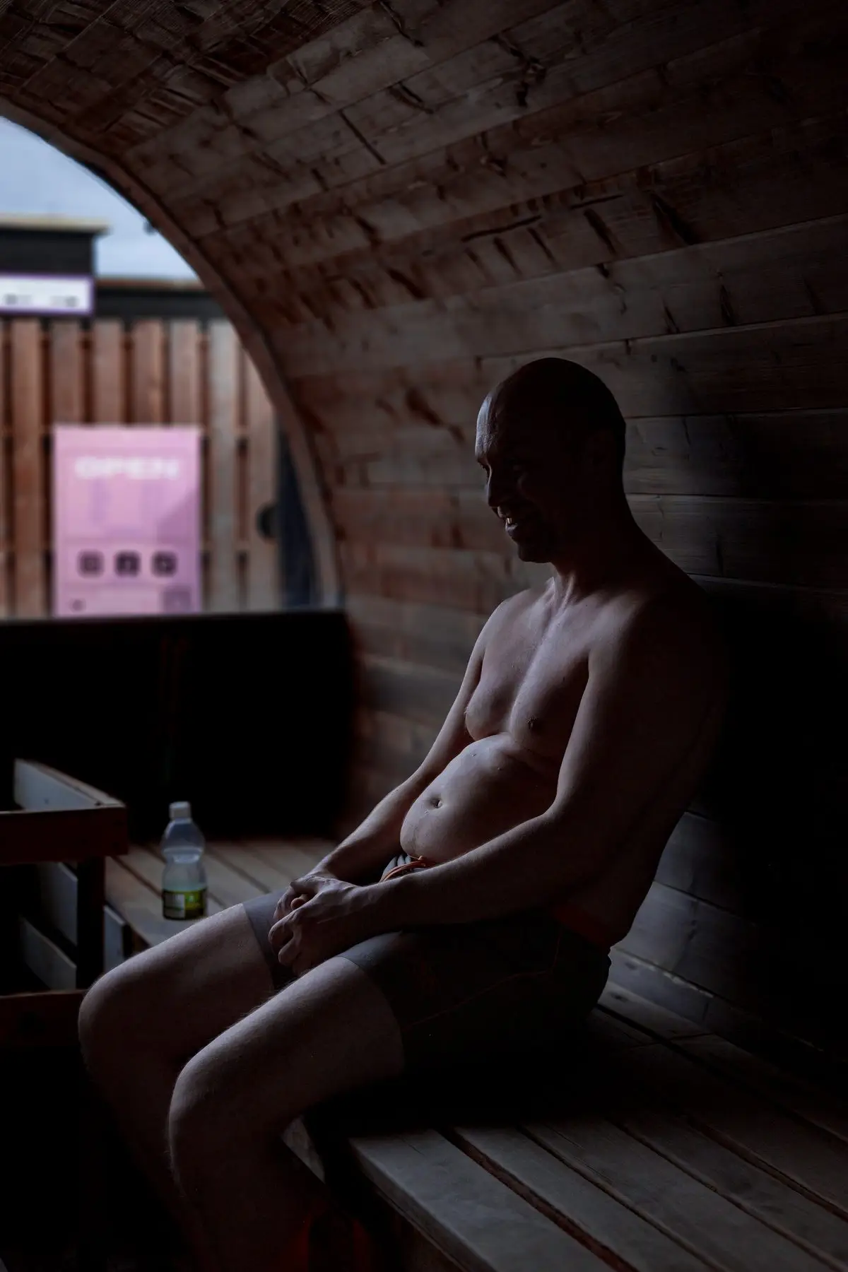 A man resting on the cedar bench inside the wood-fired barrel sauna